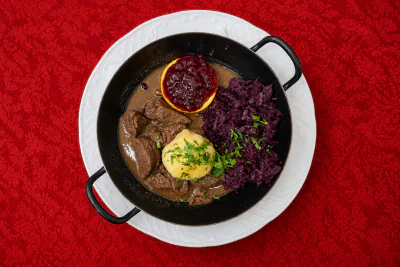 Hirsch-Edelgulasch, mit Rotkraut, Semmelknödel, Orangenscheiben und Preiselbeeren